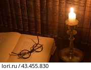Ретро-натюрморт с антикварными книгами, словарями Брокгауза и Ефрона, старинными очками и подсвечником с горящей свечой. Стоковое фото, фотограф Наталья Волкова / Фотобанк Лори