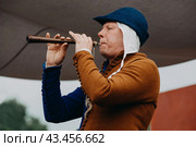 Реконструктор в костюме средневекового музыканта играет на дудочке. Исторический фестиваль «Времена и эпохи», посвященный реконструкции исторических событий. Парк Коломенское, Москва, Россия (2019) Редакционное фото, фотограф KOSIM / Фотобанк Лори