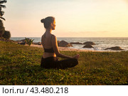 Silhouette of lady meditating sitting yoga lotus pose on ocean beach at sunset. Slim woman perform sport exercises to restore strength and spirit at sea. Healthy lifestyle concept. Copy ad text space. Стоковое фото, фотограф Aleksandr Golubev / Фотобанк Лори