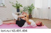 Woman Stretching Leg On Pink Mat In Home Studio. Стоковое видео, видеограф Сергей Толмачёв / Фотобанк Лори