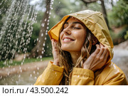 Close-up. A happy young woman in a raincoat enjoys the rain on the background of a green forest, the concept of enjoying a natural leisurely life, environment, lifestyle. Стоковое AI-изображение, AI-художник Photojuli / Фотобанк Лори