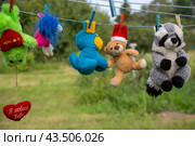 Детские мягкие игрушки сушатся на вешалке на улице во дворе жилого дома, Россия (2022 год). Редакционное фото, фотограф Николай Винокуров / Фотобанк Лори