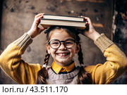 A pretty girl with glasses and books on her head. The child goes to school for the first time. A child in the fresh air. Back to school. Стоковое AI-изображение, AI-художник Photojuli / Фотобанк Лори