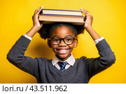 A pretty black African American girl with glasses and books in her hands. The child goes to school for the first time. A child on a yellow monochrome background. Back to school. Стоковое AI-изображение, AI-художник Photojuli / Фотобанк Лори