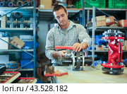Factory worker assembles shutoff valves using various tools indoor. Стоковое фото, фотограф Яков Филимонов / Фотобанк Лори