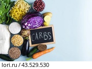 Набор продуктов, содержащих сложные углеводы и надпись на доске на английском языке "углеводы" крупным планом. Стоковое фото, фотограф Лозовая Людмила / Фотобанк Лори
