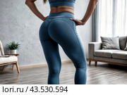 Backside close-up of woman hips woman in fit sportswear at home, domestic fitness workout. From behind of slim lady athletic glutes and legs, perfect fit. Healthy lifestyle concept. Copy ad text space. Стоковое AI-изображение, AI-художник Aleksandr Golubev / Фотобанк Лори