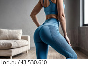 Backside close-up of woman hips woman in fit sportswear at home, domestic fitness workout. From behind of slim lady athletic glutes and legs, perfect fit. Healthy lifestyle concept. Copy ad text space. Стоковое AI-изображение, AI-художник Aleksandr Golubev / Фотобанк Лори