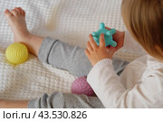 Cute baby girl playing tactile knobby balls. Young child hand plays sensory massage ball. Enhance the cognitive, physical process. Brain development. Support for Children with ADHD, autism, fidgeting. Стоковое фото, фотограф Марина Демидюк / Фотобанк Лори