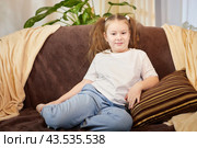 A little girl is relaxing in room on sofa. A schoolgirl is lazy after school. Teen idling or bored at home. Стоковое фото, фотограф Кривошеина Елена Леонидовна / Фотобанк Лори