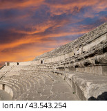 Roman Theatre in Amman, Jordan -- theatre was built the reign of Antonius Pius (138-161 CE), the large and steeply raked structure could seat about 6000 people. Against the sky with clouds (2016 год). Стоковое фото, фотограф Владимир Журавлев / Фотобанк Лори