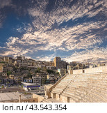 Roman Theatre in Amman, Jordan -- theatre was built the reign of Antonius Pius (138-161 CE), the large and steeply raked structure could seat about 6000 people. Against the sky with clouds (2016 год). Стоковое фото, фотограф Владимир Журавлев / Фотобанк Лори