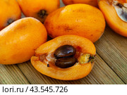 Whole and half fresh yellow loquat on wooden table. Стоковое фото, фотограф Яков Филимонов / Фотобанк Лори