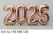 New Year 2025 celebration. Golden neon foil balloons in shape of numbers 2025 on white background. Creative holiday template footage for Party, greeting card, flyer, advertising, footage. Стоковое AI-видео, аниматор Ирина Михайличенко / Фотобанк Лори
