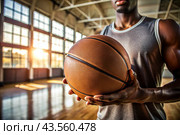 A black basketball player holds a basketball ball against the background of a basketball court. Hands and ball close-up. Стоковое AI-изображение, AI-художник Photojuli / Фотобанк Лори