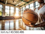 A black basketball player holds a basketball ball against the background of a basketball court. Hands and ball close-up. Стоковое AI-изображение, AI-художник Photojuli / Фотобанк Лори