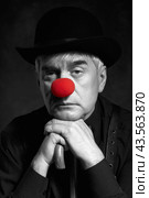 Dramatic selective color portrait of a clown against a dark background leaning on the handle of an umbrella. Стоковое фото, фотограф Сергей Пристяжнюк (Serg Zastavkin) / Фотобанк Лори