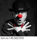 Dramatic selective color portrait of a surprised clown against a dark background with hands on chest. Стоковое фото, фотограф Сергей Пристяжнюк (Serg Zastavkin) / Фотобанк Лори