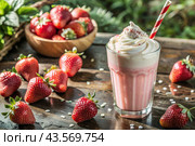Refreshing strawberry milkshake with whipped cream and a straw on the table surrounded by fresh strawberries. Стоковое AI-изображение, AI-художник Photojuli / Фотобанк Лори