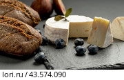 Camembert cheese with figs and blackberries and blueberries on a black wooden table. Wine food and romantic, cheese and bread delicacies. Стоковое фото, фотограф Igor Skripachev / Фотобанк Лори