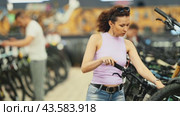 Confident stylish modern woman thoughtfully comparing bicycle models in shop, considering handlebar system, while picking perfect bike for fitness and travel. Стоковое видео, видеограф Яков Филимонов / Фотобанк Лори