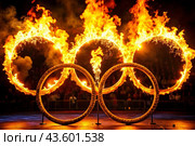 A fire show. The burning rings of the Olympic Sports Games. Стоковое AI-изображение, AI-художник Photojuli / Фотобанк Лори