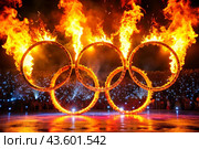 A fire show. The burning rings of the Olympic Sports Games. Стоковое AI-изображение, AI-художник Photojuli / Фотобанк Лори