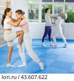 Young woman performing knee strike in midsection to female opponent during self-defense course. Стоковое фото, фотограф Яков Филимонов / Фотобанк Лори