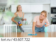 Teenage girl wiping table with rag and detergent at home kitchen. Стоковое фото, фотограф Яков Филимонов / Фотобанк Лори