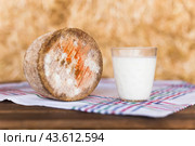 Glass of milk and a head of cheese on table in hayloft. Стоковое фото, фотограф Татьяна Яцевич / Фотобанк Лори