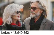 A man and a woman wearing fashionable sunglasses stand together on a busy city street. Стоковое AI-видео, аниматор Юрий Поздников / Фотобанк Лори