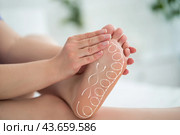 Foot massage, acupressure scheme, corns and calluses on feet, dry skin on legs, cracked heels, barefoot woman relaxing on sofa. Стоковое фото, фотограф Станислав Тарко / Фотобанк Лори