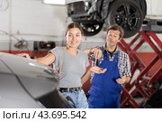 Happy female customer receiving car key from auto mechanic after repair. Стоковое фото, фотограф Яков Филимонов / Фотобанк Лори