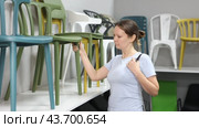 Interested woman looking for new practical chairs for his apartment in furniture store, carefully examining displayed samples. Стоковое видео, видеограф Яков Филимонов / Фотобанк Лори