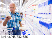 Elderly retired man buying milk in dairy section of the supermarket. Стоковое фото, фотограф Татьяна Яцевич / Фотобанк Лори