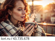 A red-haired, beautiful woman wrapped in a plaid with a mug of hot coffee on a beautiful patio in the rays of the setting sun. The girl inhales the aroma of the drink. Comfort and harmony. Стоковое AI-изображение, AI-художник Photojuli / Фотобанк Лори