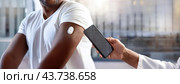 A close-up of a person's arm with a wearable device of real-time control of health through continuous glucose monitoring CGM system being scanned by a smartphone, showcasing health technology. Стоковое AI-изображение, AI-художник Igor Tichonow / Фотобанк Лори