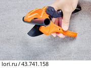 Piece of plastic pipe lies between blades of pipe cutter with ratcheting mechanism, plumber hand holds tool. Стоковое фото, фотограф Владимир Григорьев / Фотобанк Лори