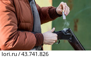 Двуствольное ружье и стреляная гильза в руках мужчины и дым от выстрела (2017 год). Редакционное фото, фотограф Евгений Зимин / Фотобанк Лори