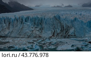 A wall of blue ice with cracks and sharp peaks rises above the glacial lake. Melted ice floes float in turquoise water. The glacier massif extends to the horizon. Fog. Perito Moreno. El Calafate. Стоковое фото, фотограф Вера Ивановна Кубарева / Фотобанк Лори