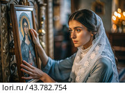 Portrait of a beautiful young woman in a headscarf in an Orthodox church. A girl prays in a church against the background of icons. Стоковое AI-изображение, AI-художник Photojuli / Фотобанк Лори