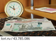 Российские денежные купюры лежат на клавиатуре компьютера на фоне часов. Стоковое фото, фотограф Сергей Овчинников / Фотобанк Лори