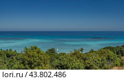Amazing seascape. A sailboat, a tiny island, is visible in the boundless turquoise-aquamarine ocean. Lush tropical green vegetation in the foreground. Clear blue sky. Copy space. Madagascar. Стоковое фото, фотограф Вера Ивановна Кубарева / Фотобанк Лори