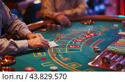 A man is strategically playing roulette at a lively casino table, enjoying the atmosphere. Стоковое AI-изображение, AI-художник Юрий Поздников / Фотобанк Лори