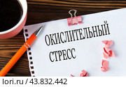 ОКИСЛИТЕЛЬНЫЙ СТРЕСС - слова на белом листе на деревянном коричневом фоне с чашкой кофе и ручкой. Стоковое фото, фотограф Жанна Гапанович / Фотобанк Лори