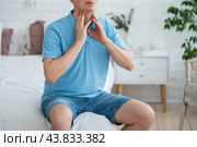 Thyroid gland inflammation, sore throat and cough, man with neck pain on gray background. Стоковое фото, фотограф Станислав Тарко / Фотобанк Лори