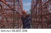 A builder in a hard hat carries red metal beams строитель в каске несет красные металлические балки. Стоковое видео, видеограф Опока Алексей / Фотобанк Лори