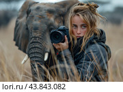 A Young Photographer Captures Wildlife Moments in a Grassland With an Elephant Nearby. Стоковое AI-изображение, AI-художник Сергей Толмачёв / Фотобанк Лори
