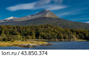 The beautiful landscape of Patagonia. Autumn. There is yellow grass on the shore of a blue lake. There is a forest growing on the mountainside. A snow-covered peak against the sky,clouds. Lapataia Bay. Стоковое фото, фотограф Вера Ивановна Кубарева / Фотобанк Лори