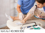 Cropped male doctor shows problem areas of varicose veins on mature woman patients leg. Стоковое фото, фотограф Яков Филимонов / Фотобанк Лори